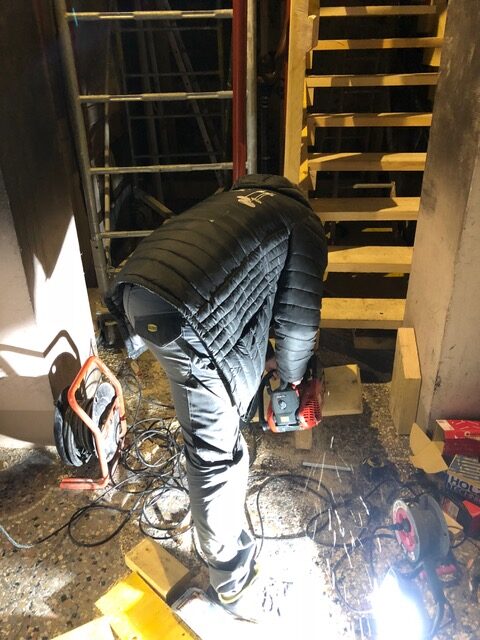 Employé de la société ISM 38 montant un escalier provisoire dans un appartement après un incendie